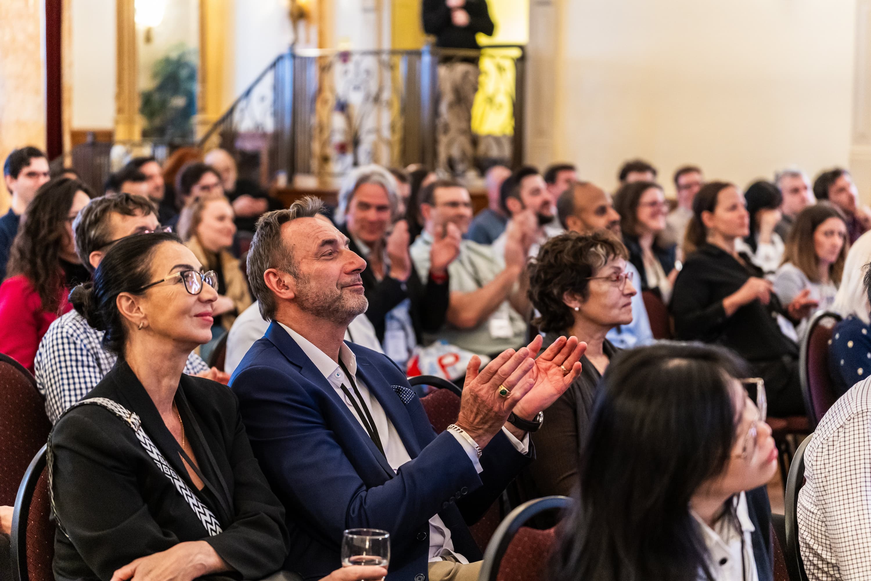 A diverse audience at an AquaAction event, attentively listening and applauding, reflecting engagement, networking, and support for water innovation initiatives.