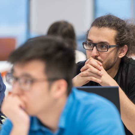 A group of young individuals attentively listening during a workshop or educational session, illustrating focus, curiosity, and critical thinking. A group of young individuals attentively listening during a workshop or educational session, illustrating focus, curiosity, and critical thinking.